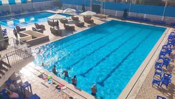 A swimming pool with multiple lanes, lounge chairs, and sunbeds.