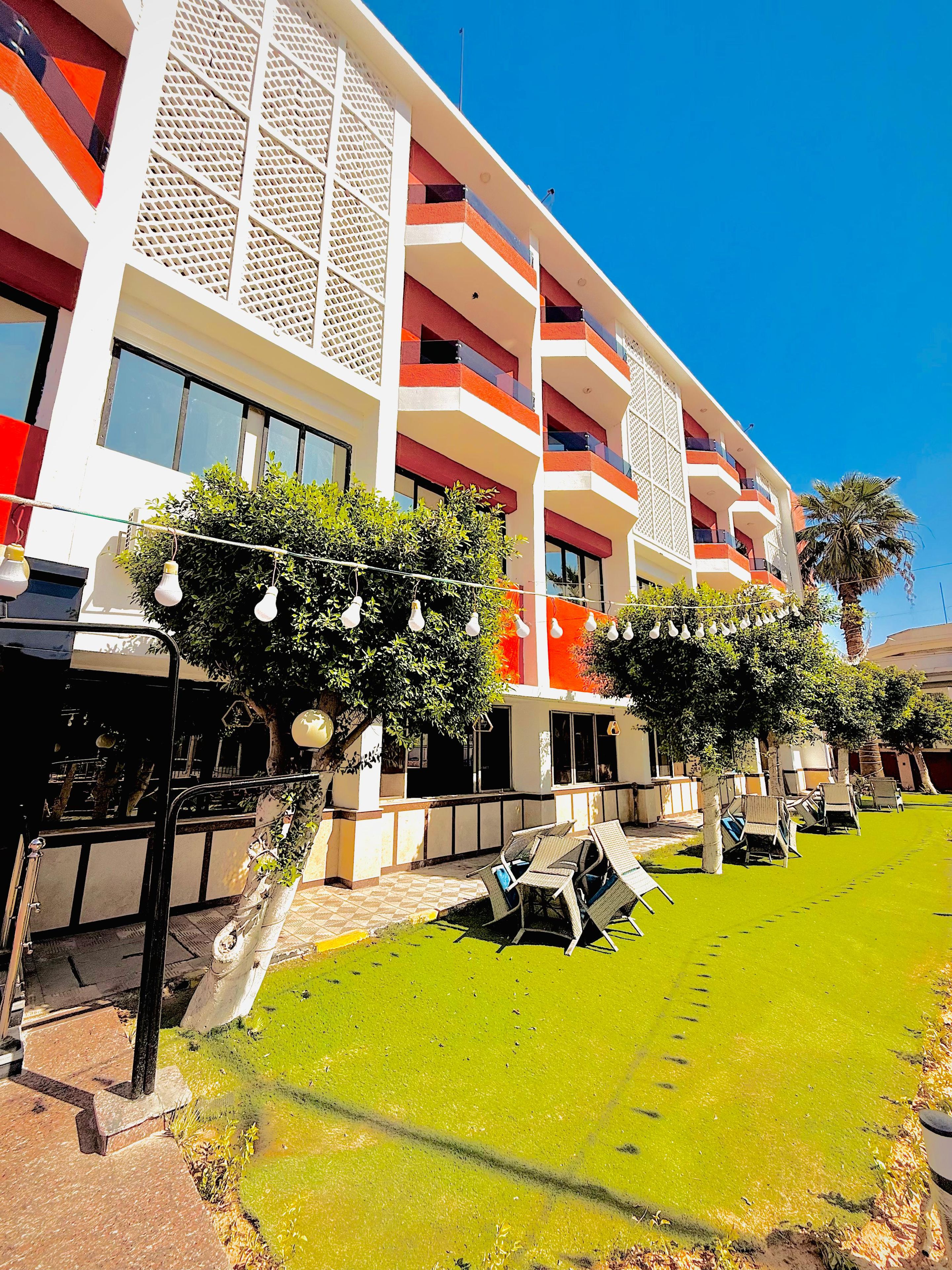A hotel with multiple balconies, outdoor seating, and a well-maintained lawn.