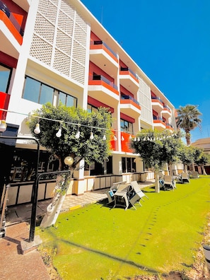 A hotel with multiple balconies, outdoor seating, and a well-maintained lawn. - Merit Amon Hotel (Akhmim)
