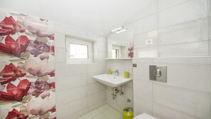 Ein Badezimmer mit einem weißen Waschbecken, einem Spiegel, einem Fenster und einer Toilette.