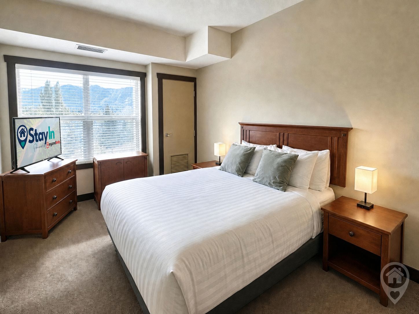 Habitación de hotel con una cama grande, dos mesitas de noche con lámparas, un armario, un televisor y una ventana con persianas.