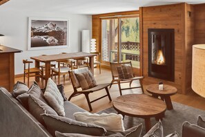 Ein gemütliches Wohnzimmer mit Kamin, Holzmöbeln und einem großen Fenster mit Aussicht.