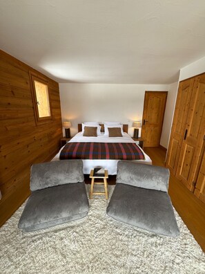 Ein Schlafzimmer mit einem Bett, zwei Nachttischen, einem Holzschrank und einem kleinen Hocker.