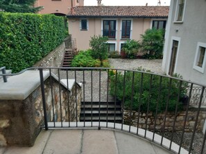 A curved staircase with a metal railing leading to a building with a tiled roof and windows.