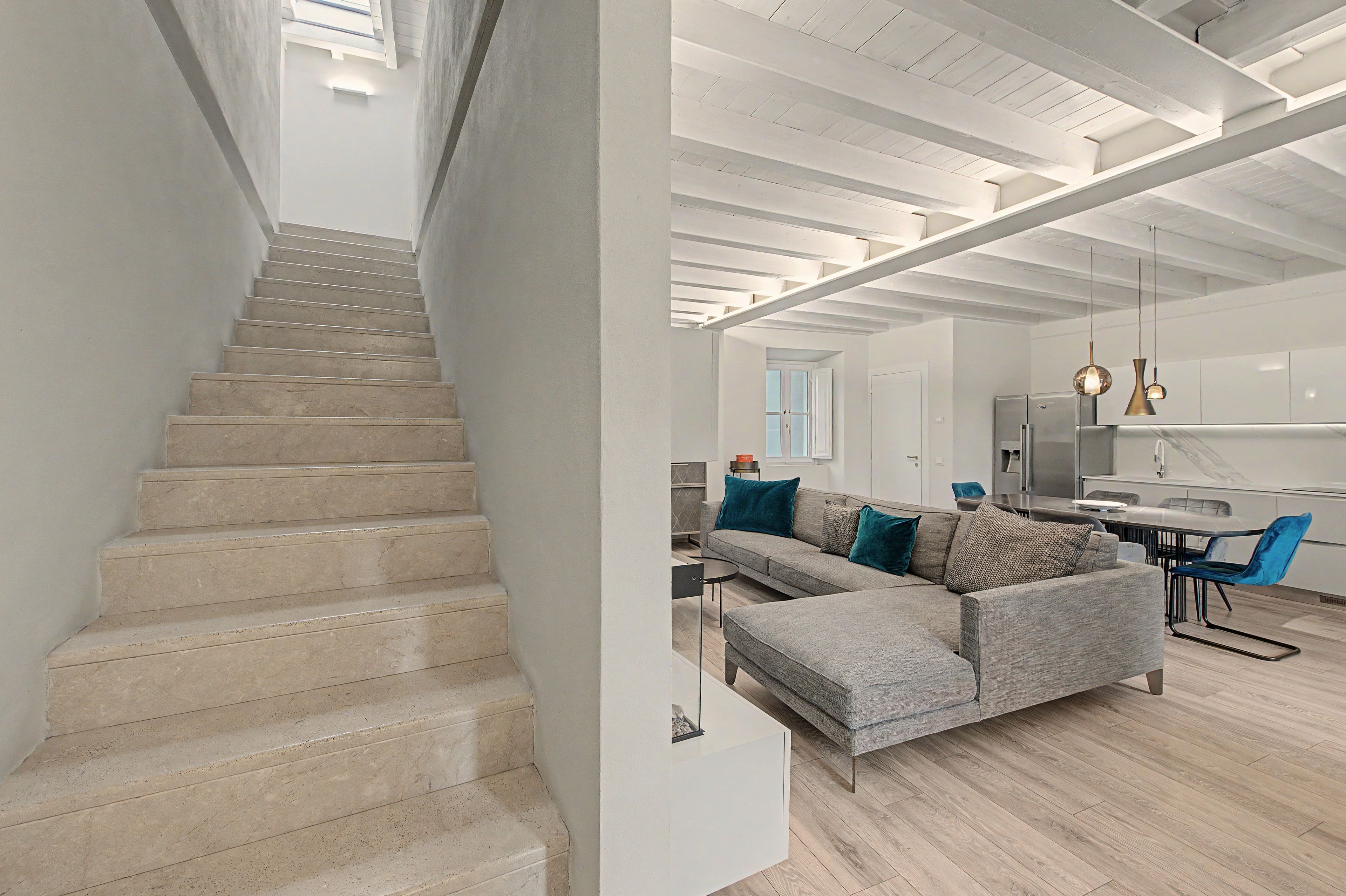 A modern interior with a staircase leading to a living area, a dining area, and a kitchen.