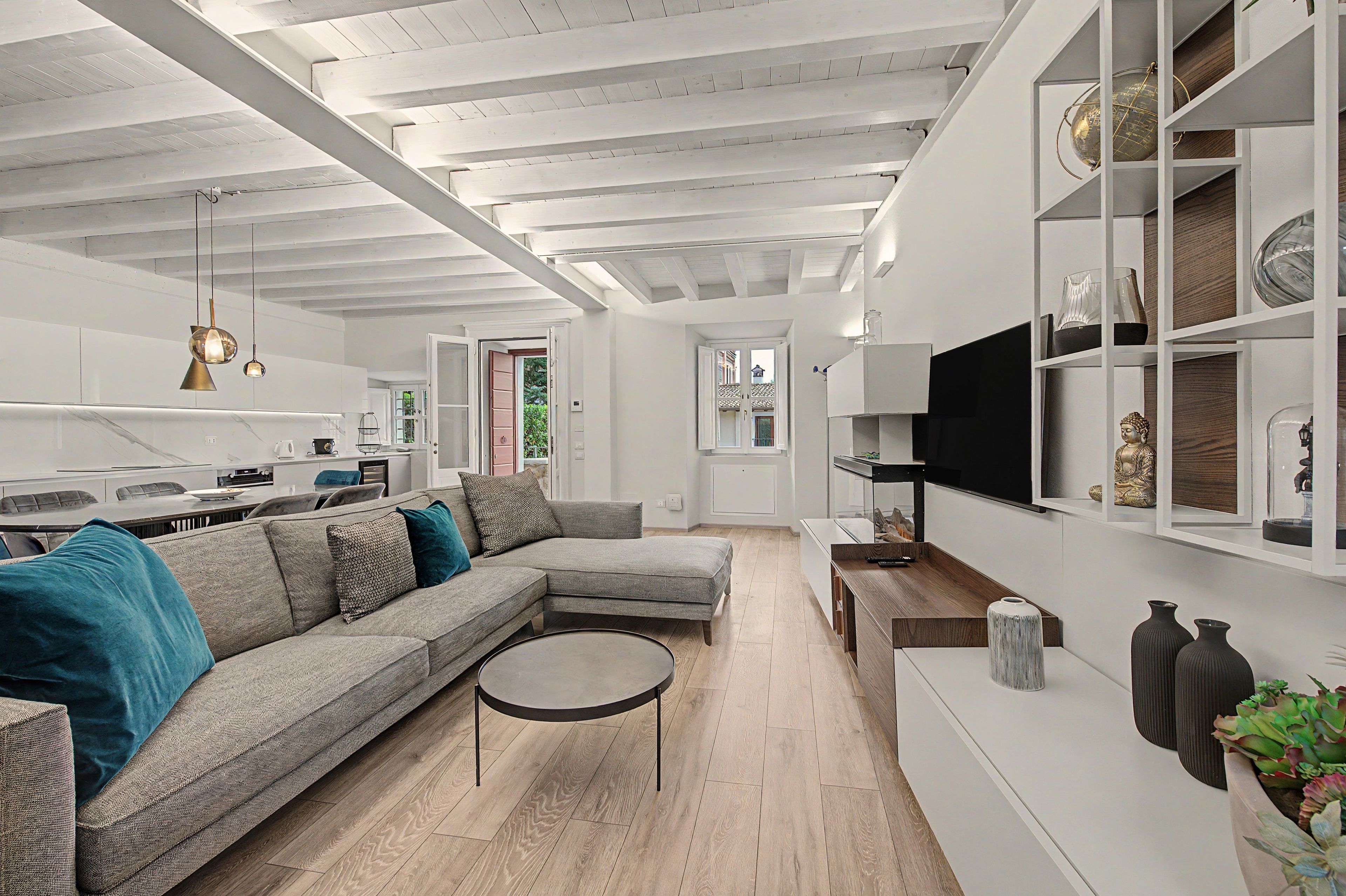 A modern living room with a sectional sofa, a round coffee table, and a TV mounted on the wall.