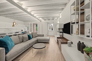 A modern living room with a sectional sofa, a round coffee table, and a TV mounted on the wall.