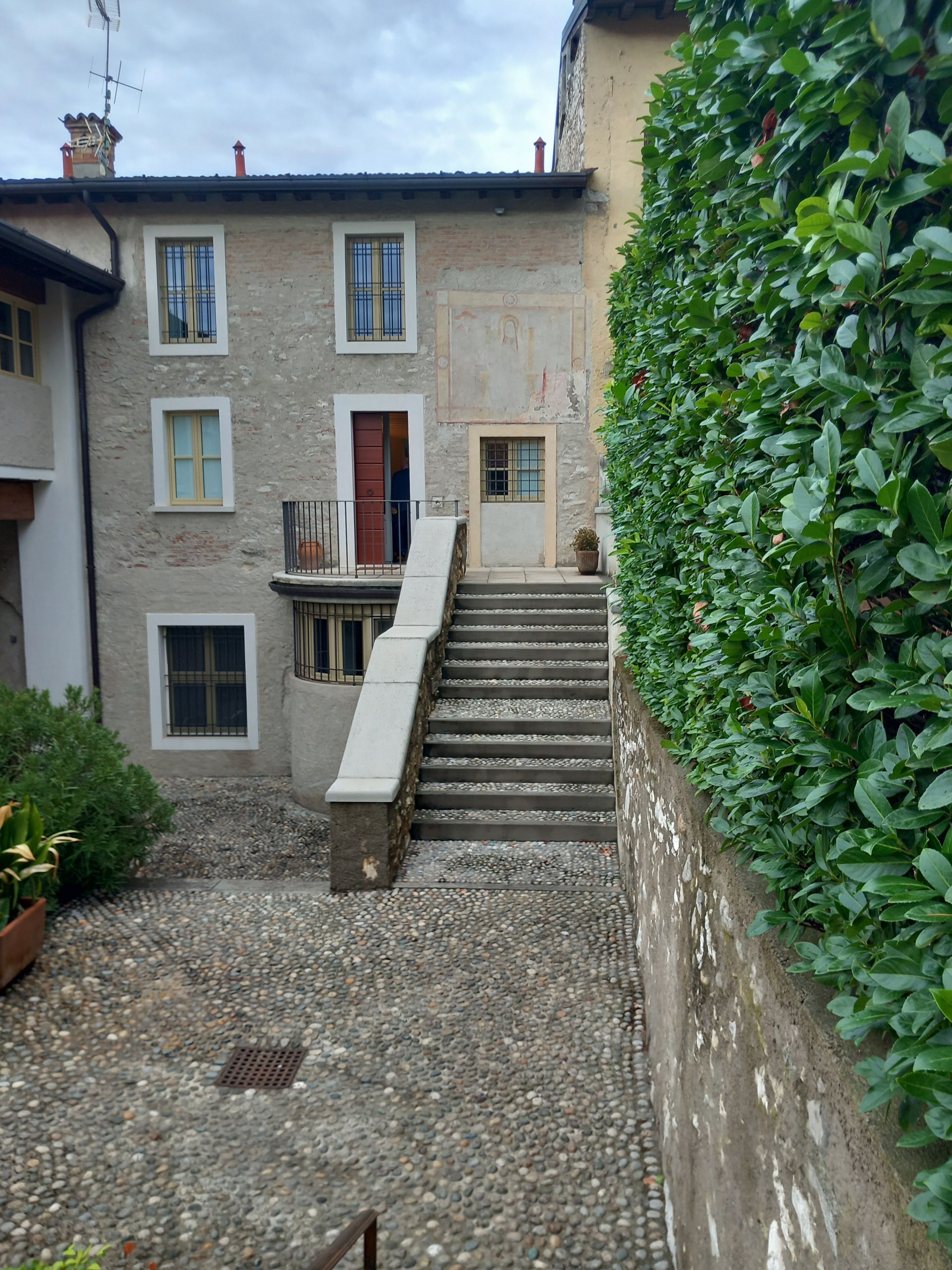 A stone building with multiple windows and a staircase leading to a door.