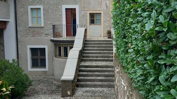 A stone building with multiple windows and a staircase leading to a door.