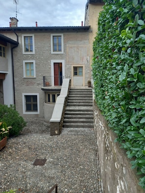 A stone building with multiple windows and a staircase leading to a door.