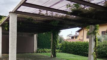 A covered outdoor area with a patterned floor, concrete pillars, and a mesh roof.