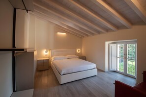 A bedroom with a bed, bedside tables, a nightstand, a window, and a door.