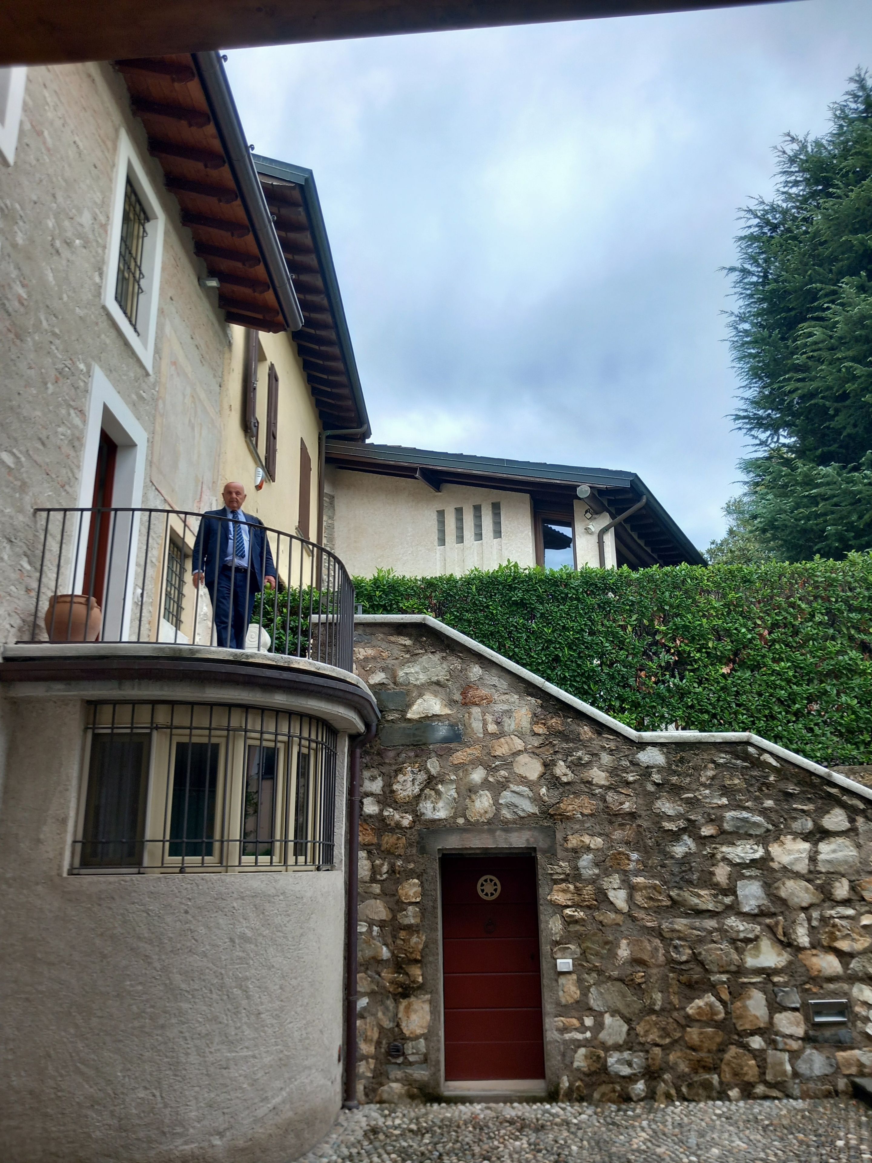 Ein Gebäude aus Stein mit einer roten Tür und einem Balkon, auf dem eine Person steht.