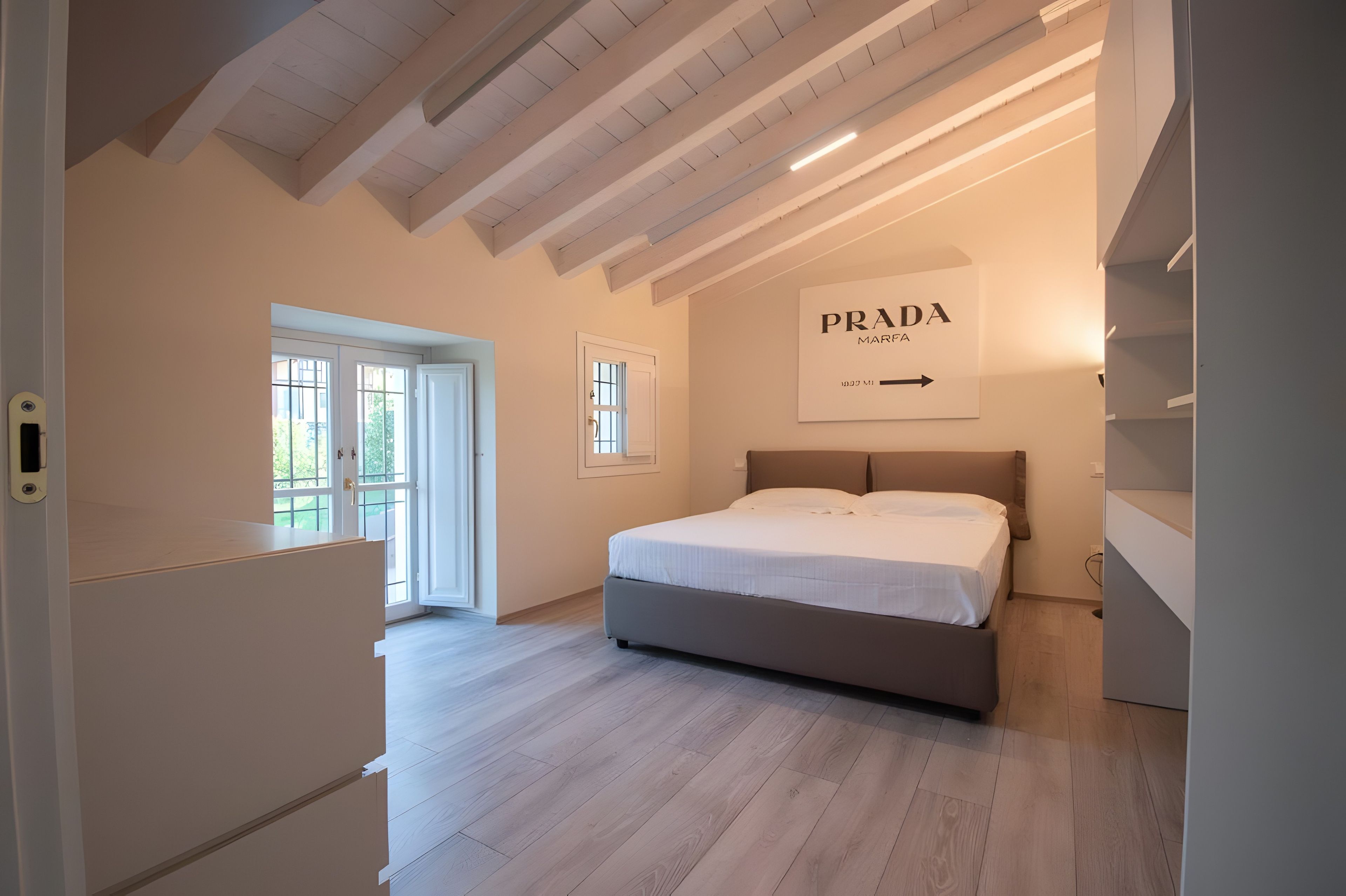 A bedroom with a bed, a wardrobe, a door, and a wall-mounted sign.