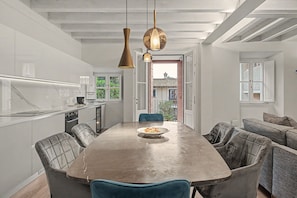 A modern kitchen with a central island, pendant lighting, and a view of a balcony.