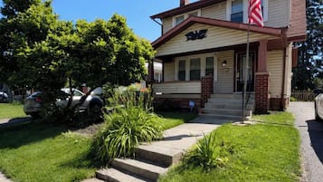 Uma casa de dois andares com varanda frontal, uma bandeira e uma caixa de correio.
