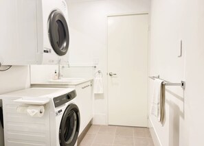 Una safareig reduït amb rentadora, assecadora i una porta.