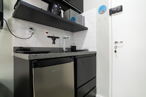 Eine Küche mit einem Edelstahl-Kühlschrank, einem eingebauten Backofen und einer Arbeitsplatte mit Wasserkocher und Kaffeemaschine.