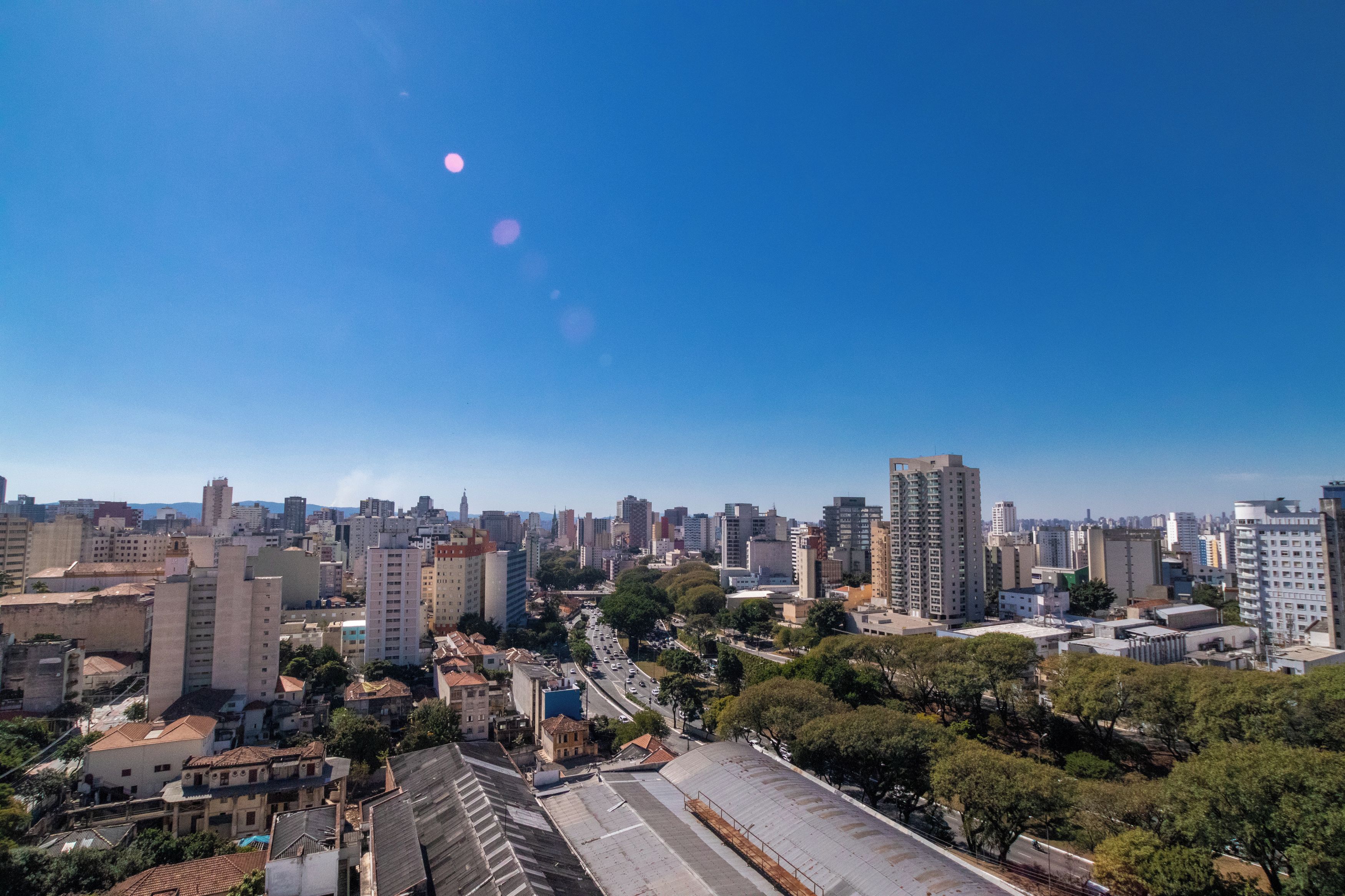 A cityscape with a mix of high-rise and low-rise buildings, a clear sky, and a road with vehicles.
