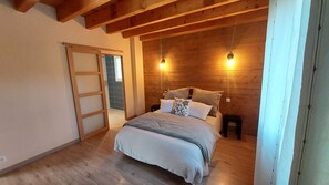 A bedroom with a wooden ceiling, a bed with pillows, a nightstand, and a sliding door.