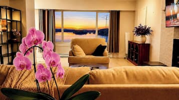 A living room with a sofa, a coffee table, and a potted orchid.