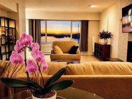 Una sala de estar con un sofá, una mesa de centro y una orquídea en maceta.