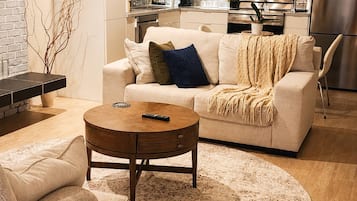 A modern living room with a sofa, coffee table, and a kitchen in the background.