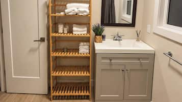 A bathroom with a wooden shelf unit, a sink, and a mirror.
