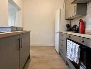 A compact kitchen with a built-in oven, a coffee maker, and a red fire extinguisher. - Stylish Home In Hartlepool, Free Parking & Wifi (Hartlepool)