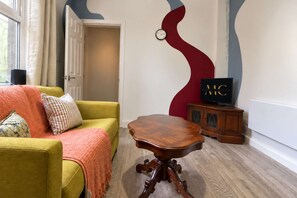 A living room with a yellow sofa, a wooden coffee table, a television on a wooden cabinet, and a wall clock. - Stylish Home In Hartlepool, Free Parking & Wifi (Hartlepool)
