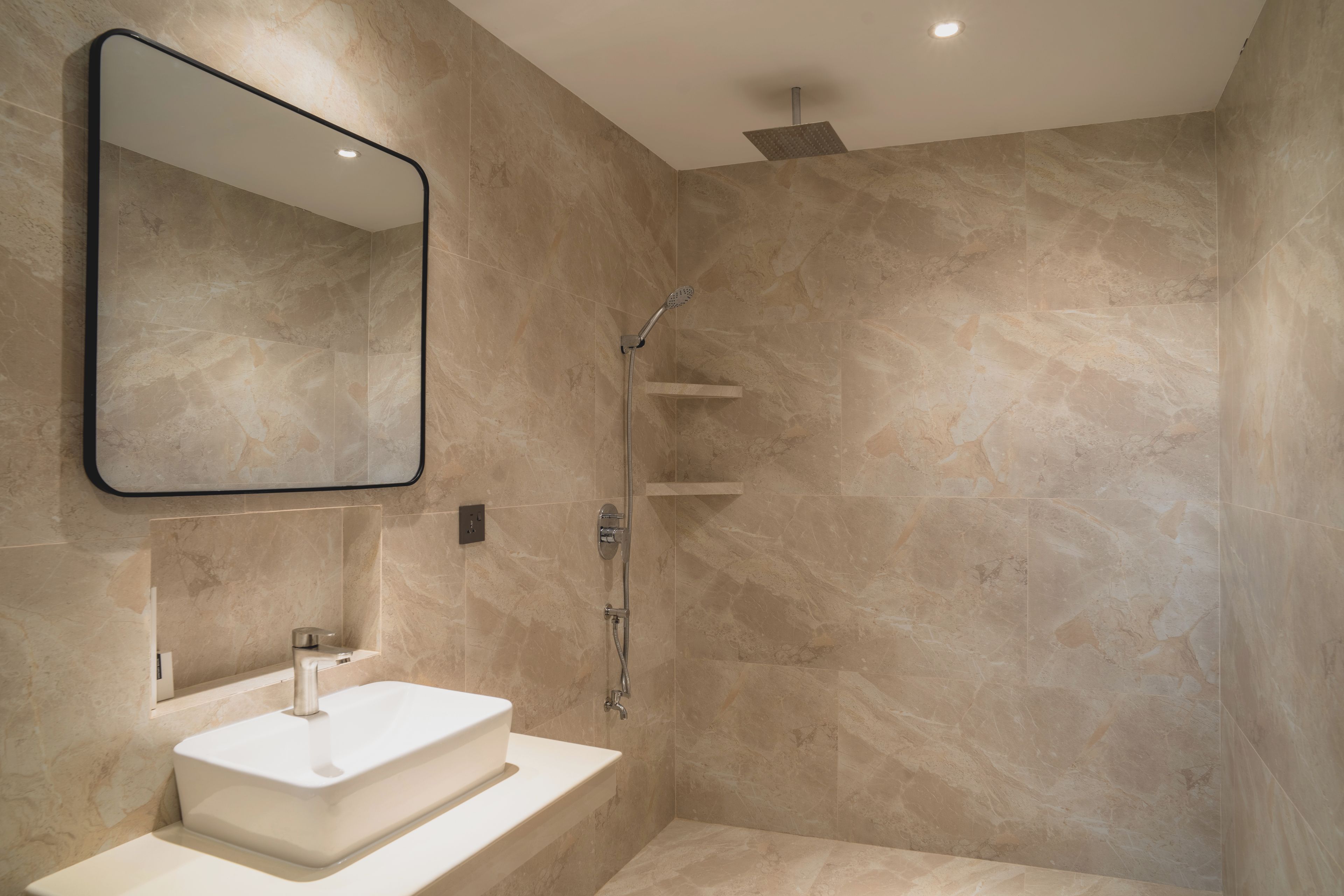 Une salle de bain moderne avec un miroir rectangulaire, un lavabo blanc et une cabine de douche.