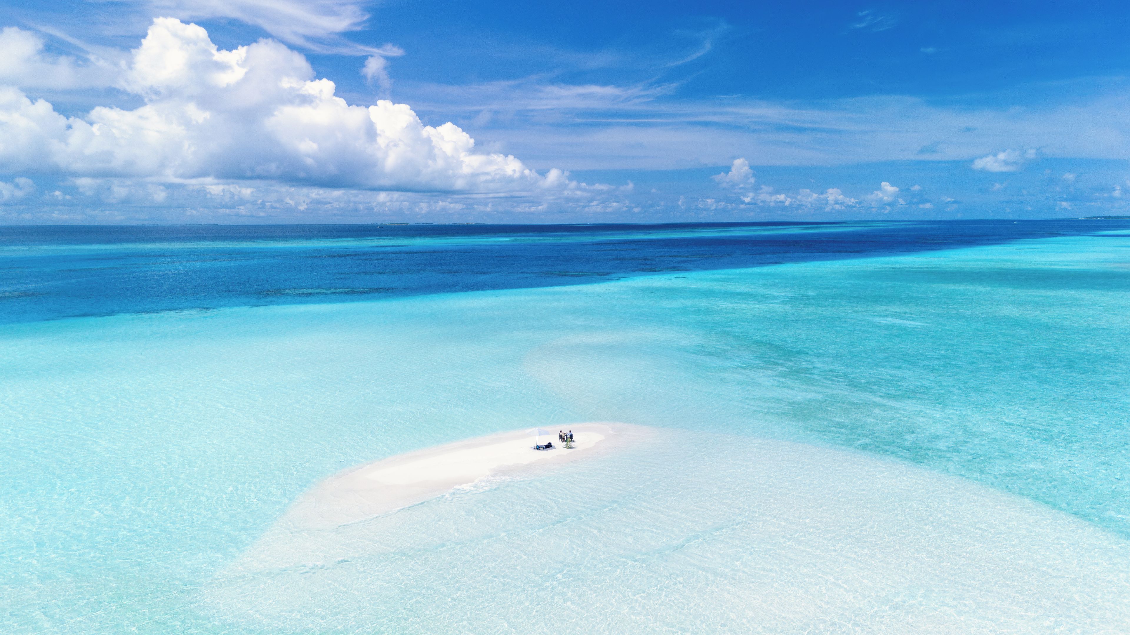 A clear turquoise sea with a white sandy beach and a small group of people.