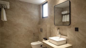 Un baño moderno con inodoro, lavamanos y espejo.