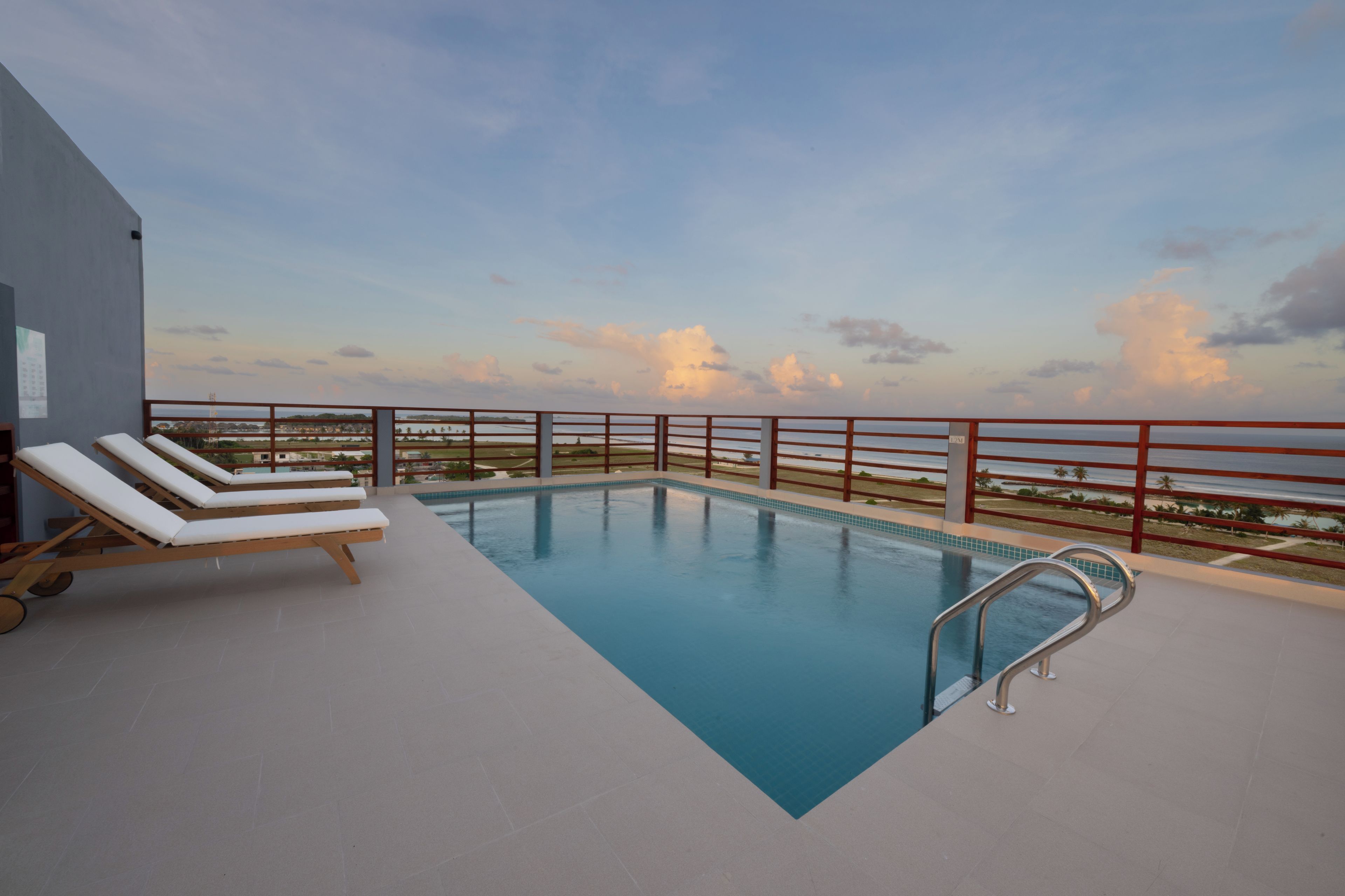 A rooftop pool with lounge chairs and a view of the ocean.