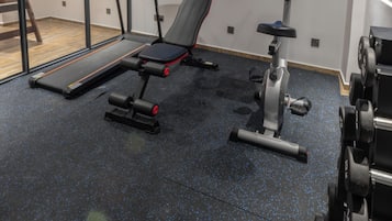 Un gimnasio con equipamiento de ejercicio, cinta de correr y máquina de remo.