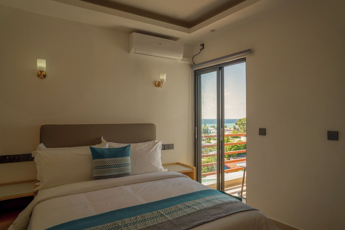 Una habitación de hotel con cama, vista al océano y balcón.
