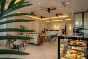 A modern hotel lobby with a seating area, a reception desk, and a view of the sky lounge. - Atollios Skyview Hotel (Huraa)