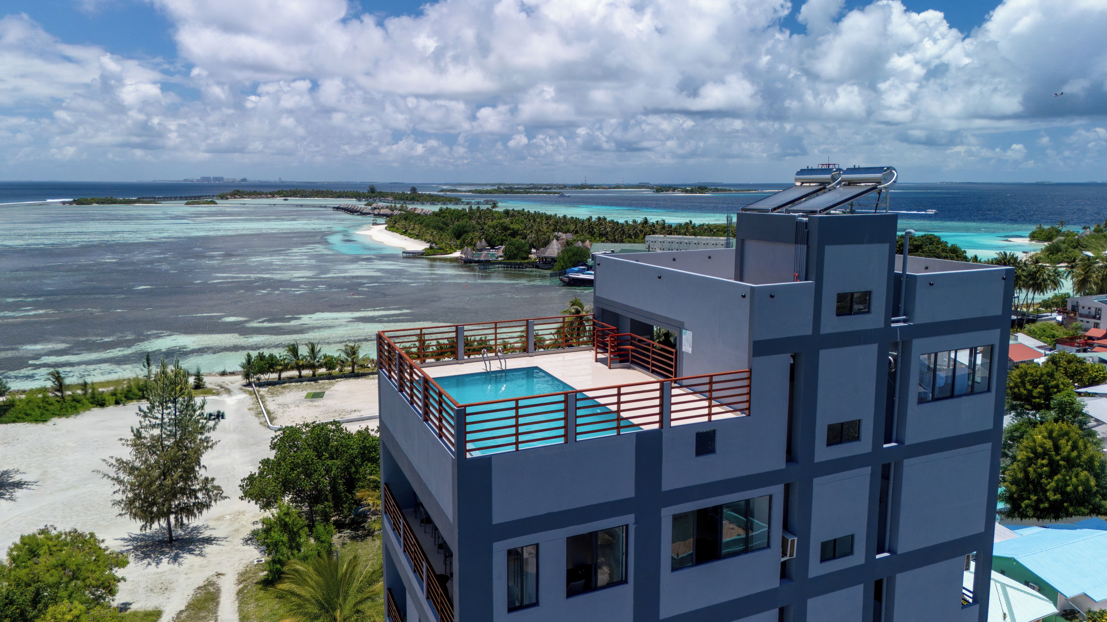 A modern hotel with a rooftop pool, ocean views, and a beach area.