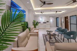 Un moderno vestíbulo de hotel con un mostrador de recepción, zona de estar y ventiladores de techo.