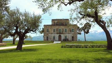 A historic building with a central courtyard, surrounded by trees and a well-maintained lawn.