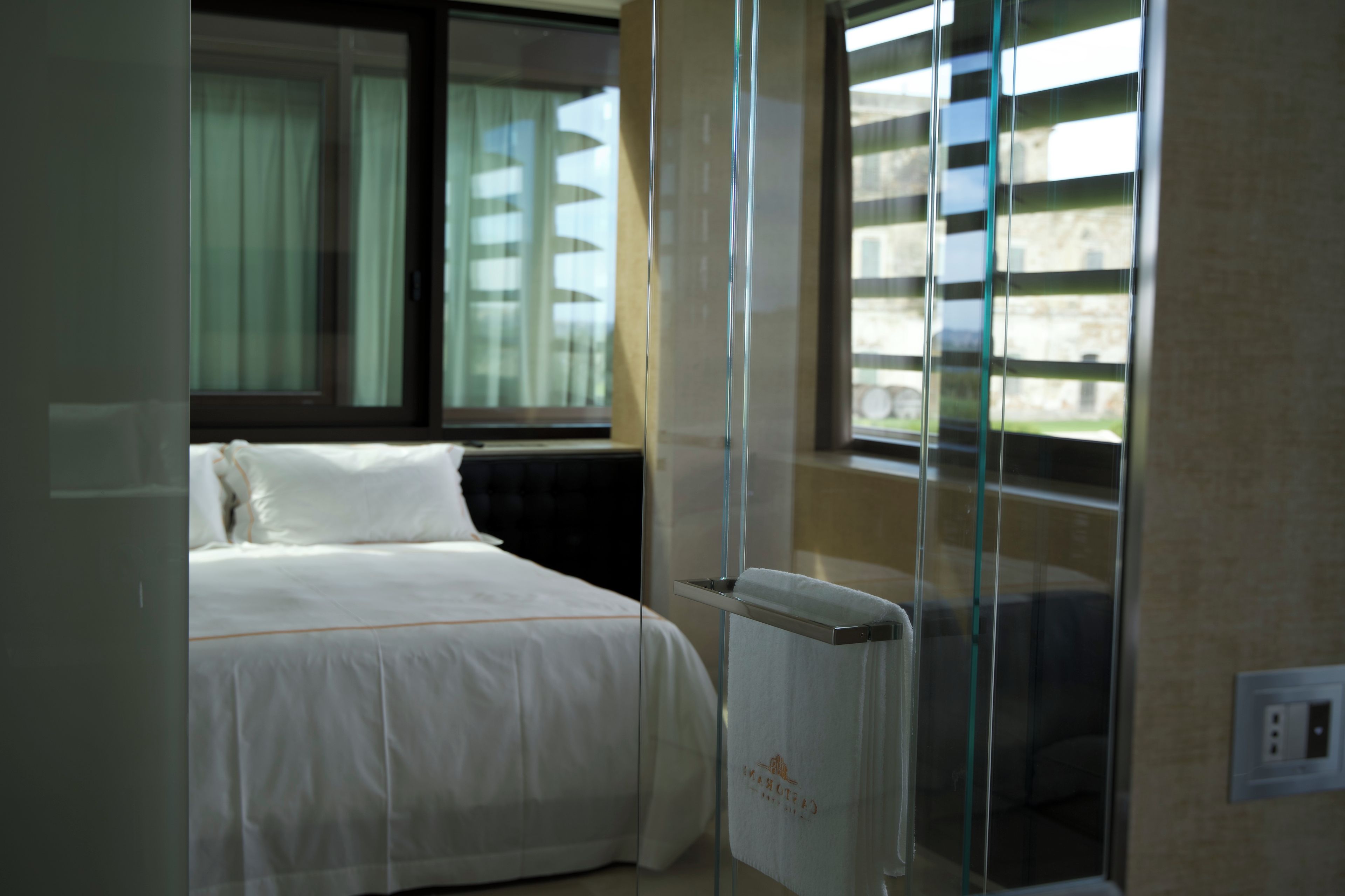 Ein Hotelzimmer mit Bett, Fenster mit Jalousien und Heizkörper.