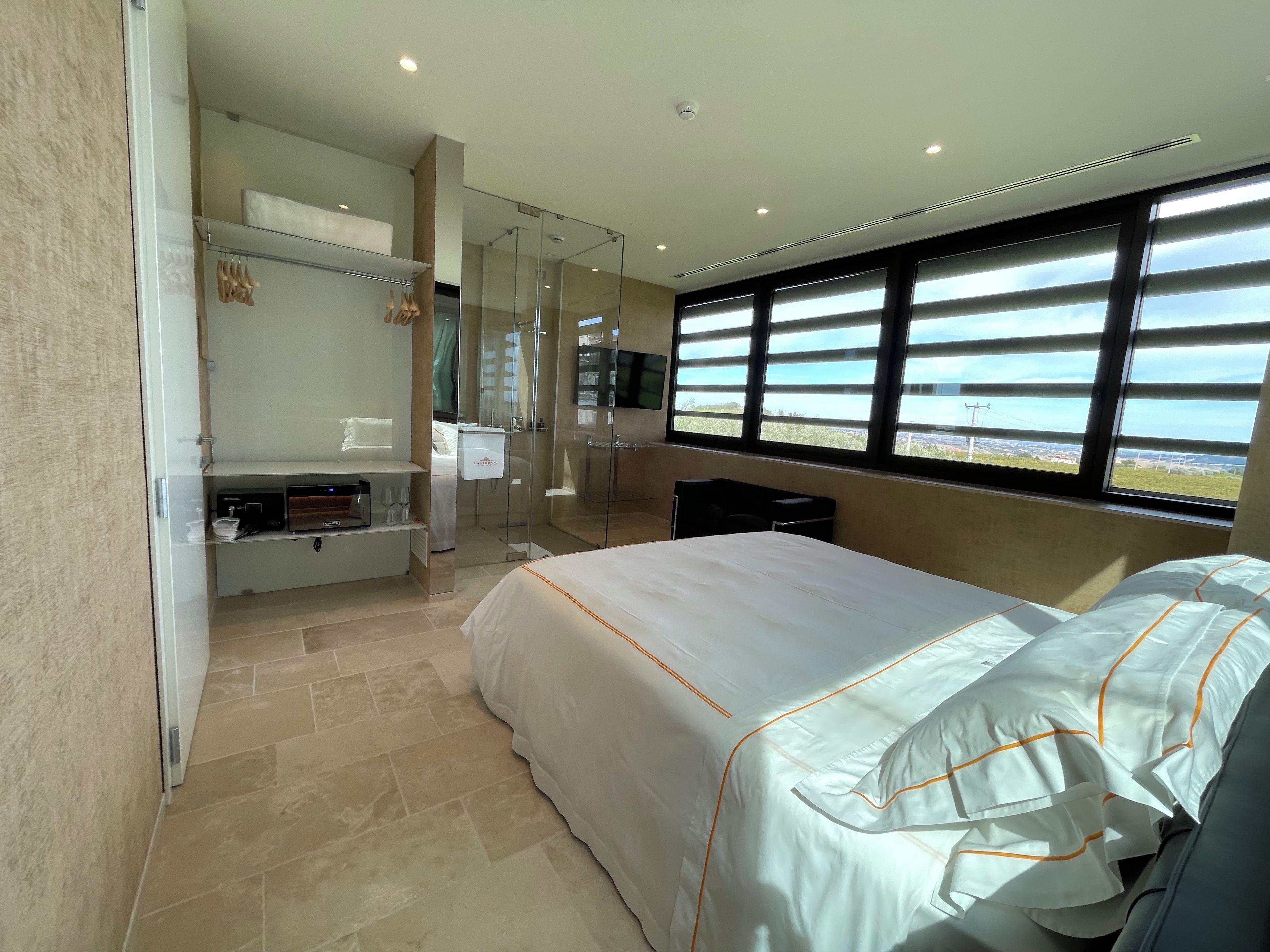 Ein Hotelzimmer mit Bett, einer Sitzecke mit Tisch, einer Dusche und einem großen Fenster mit Blick.