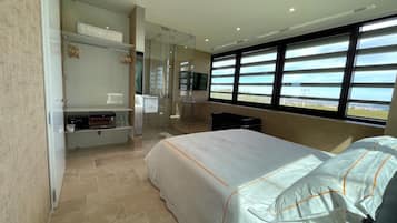 A hotel room with a bed, a seating area with a table, a shower, and a large window with a view.