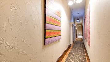 A hallway with textured walls, a patterned carpet, and artwork.