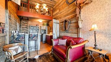 Ein rustikales Interieur mit einem roten Ledersofa, Holzmöbeln und einer Chandelier.
