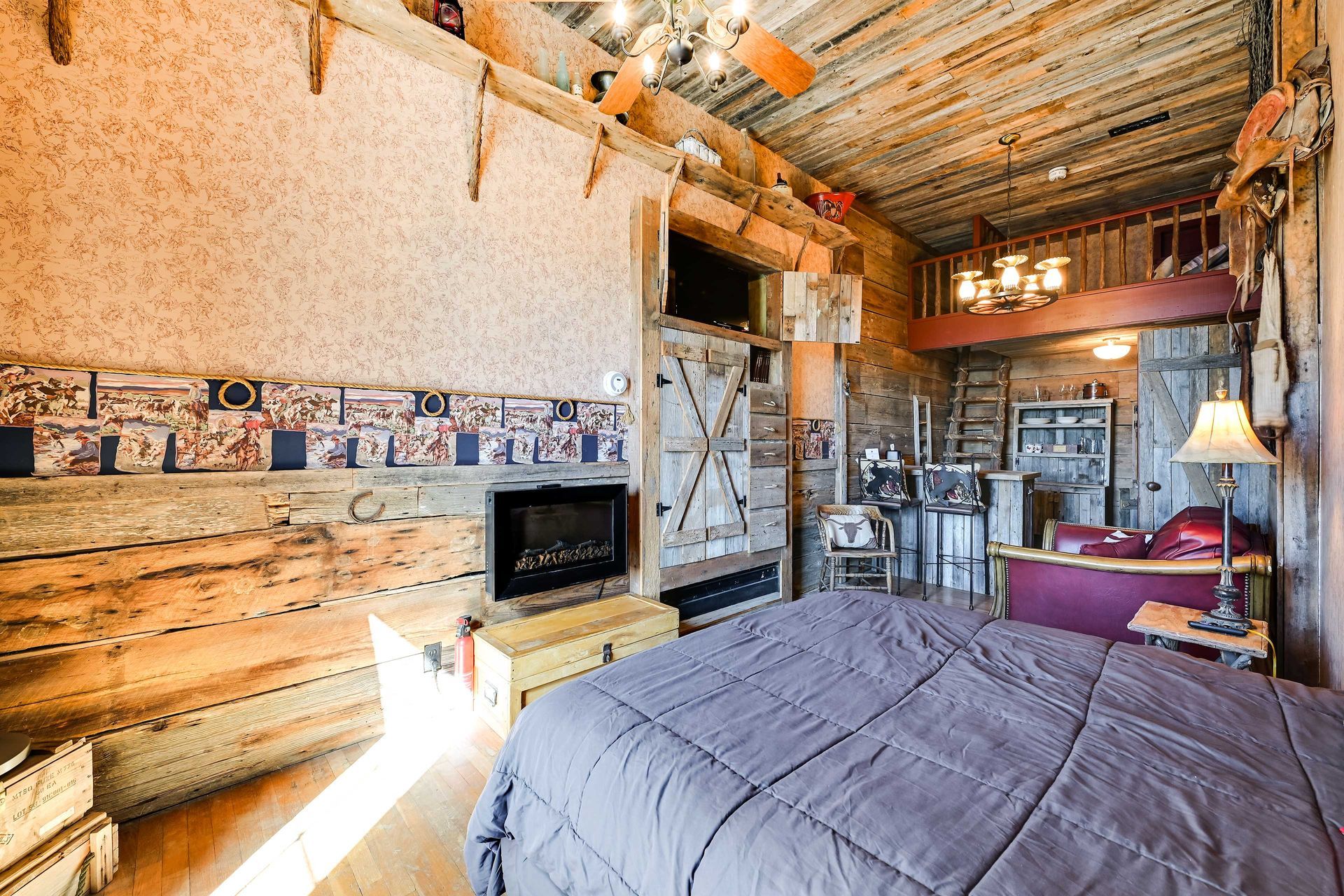 A rustic interior with a wooden ceiling, a fireplace, a bed, and a bar area.