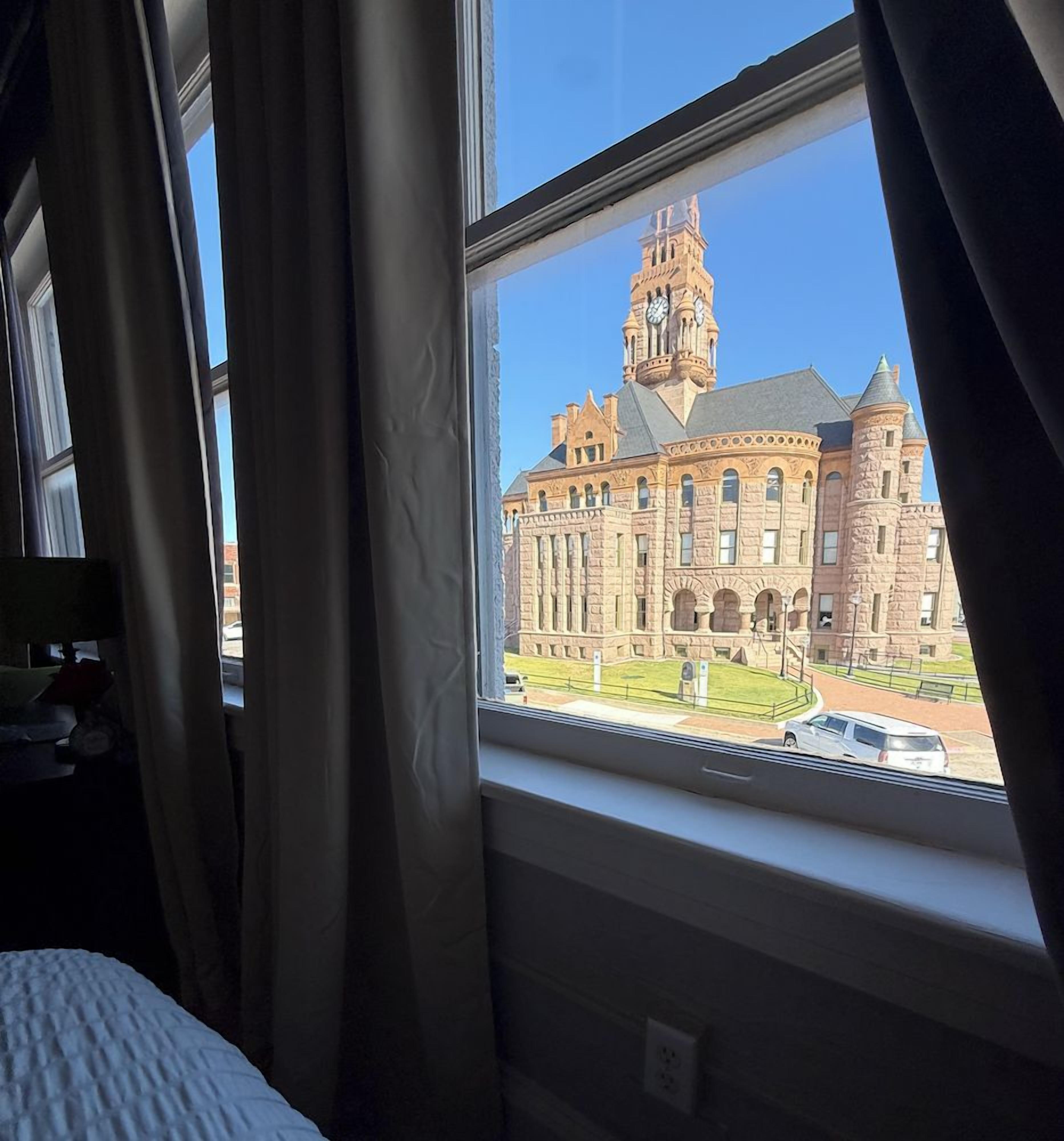 A room with a large window overlooking a historic building with a clock tower.