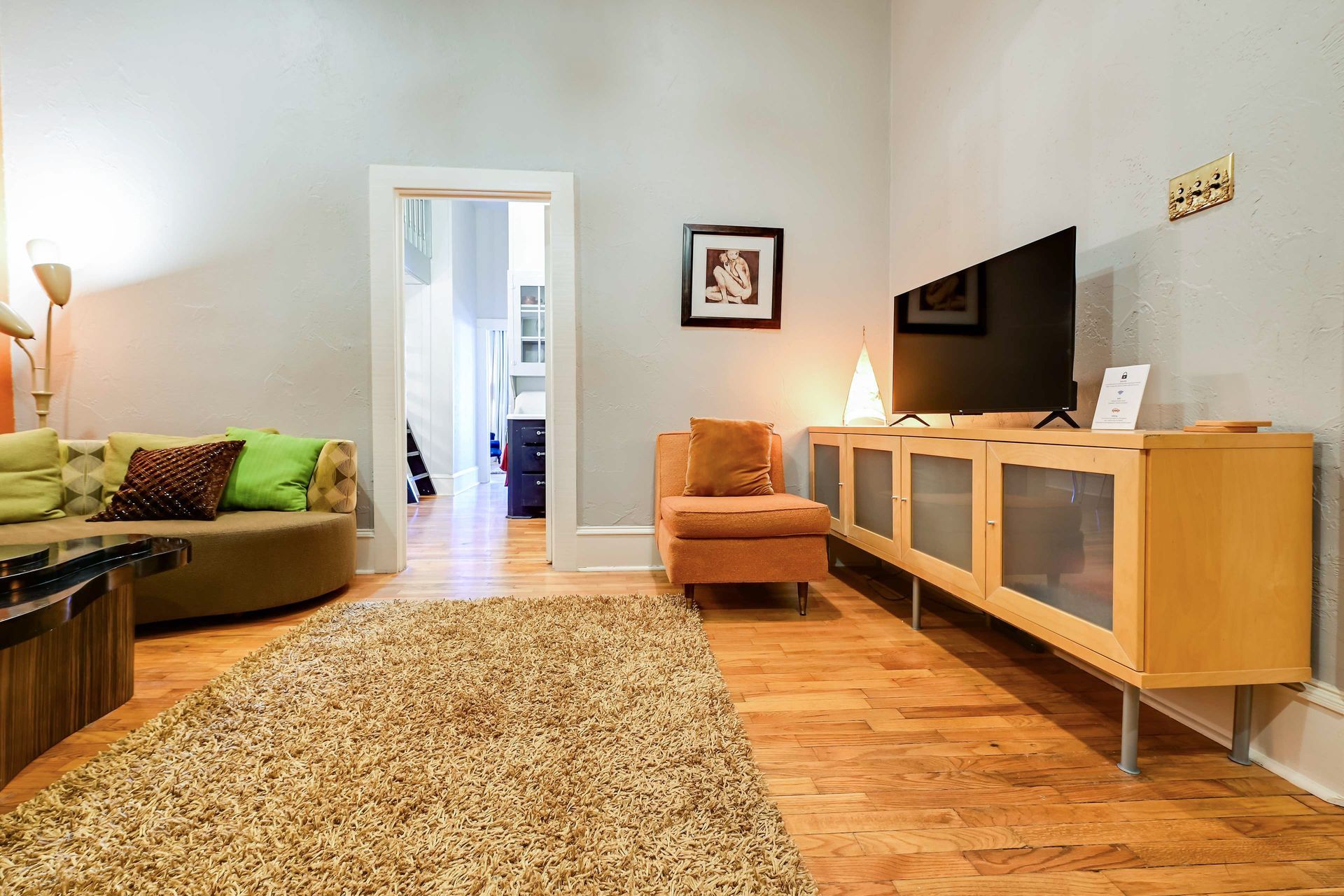 A living room with a sofa, armchair, TV, and wooden cabinet.