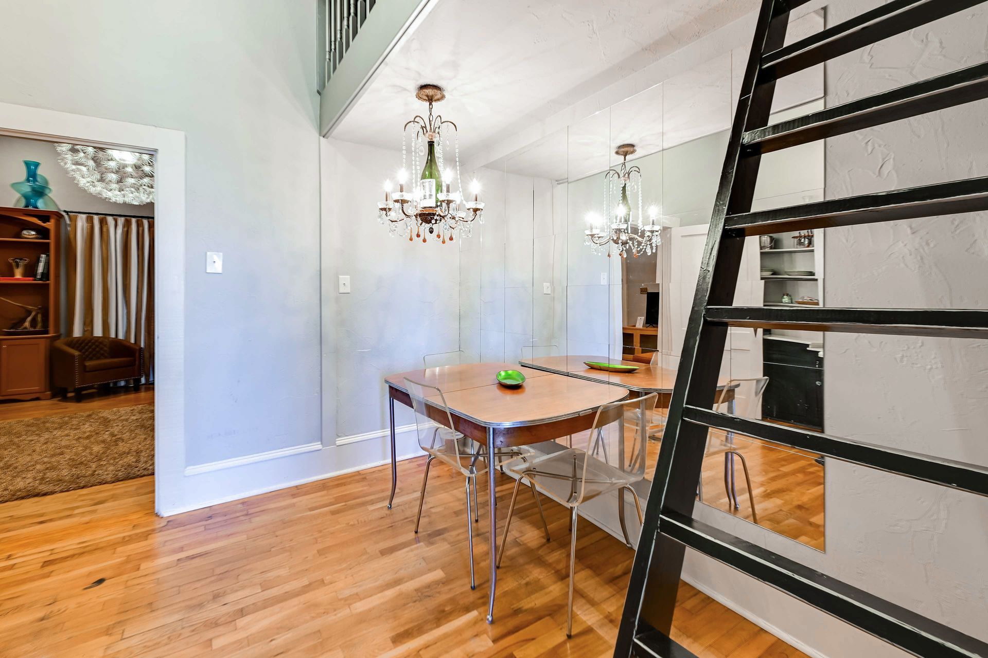 A dining area with a wooden table, clear chairs, and a chandelier.