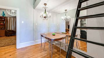 A dining area with a wooden table, clear chairs, and a chandelier.